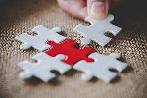 A puzzle piece being added to a group of puzzle pieces.
